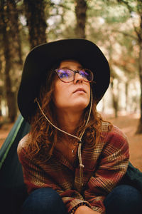 Young woman looking up sitting at forest