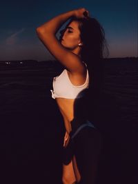 Beautiful woman standing at beach against sky