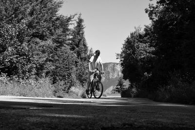 Man riding bicycle on road against trees