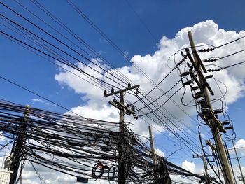 Low angle view of electricity pylon against blue sky