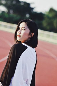 Portrait of young woman standing on running track