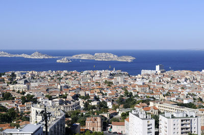 High angle view of townscape by sea against clear sky