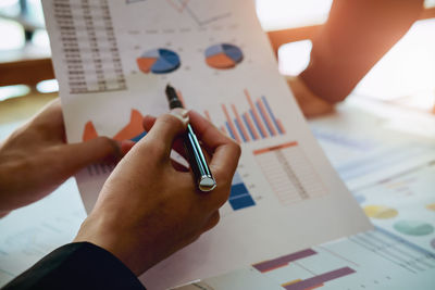 Midsection of person holding paper with text on table
