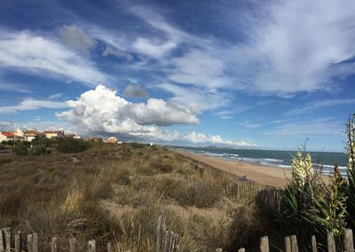 Scenic view of beach against cloudy sky