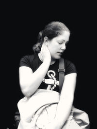 Girl looking away while sitting against black background