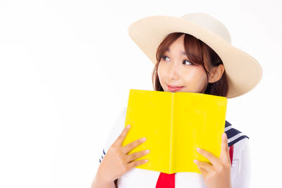 Portrait of woman holding hat against white background