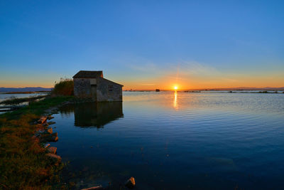 Building by sea against sky during sunset