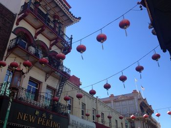 Low angle view of lanterns hanging in city against sky