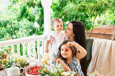 Cheerful mother with kids sitting by dining table