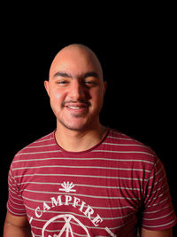 Portrait of smiling young man against black background