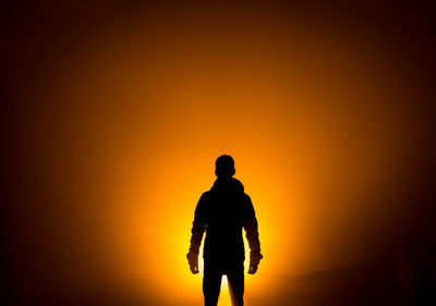 Silhouette man standing against orange sky