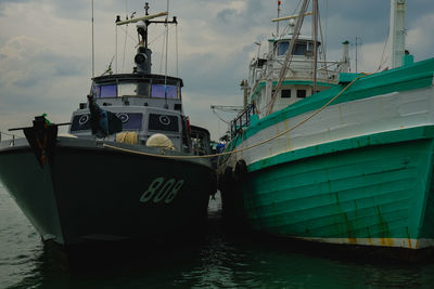 Boats moored at harbor against sky