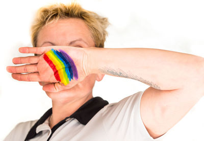 Person with rainbow flag paint on hand against white background