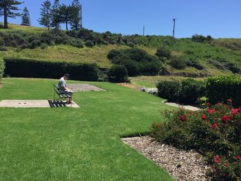 Man sitting on grassy field against clear sky