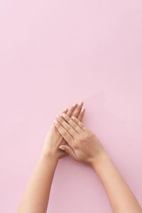 Close-up of woman hand against pink background