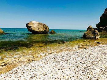 Rocks on beach against clear sky