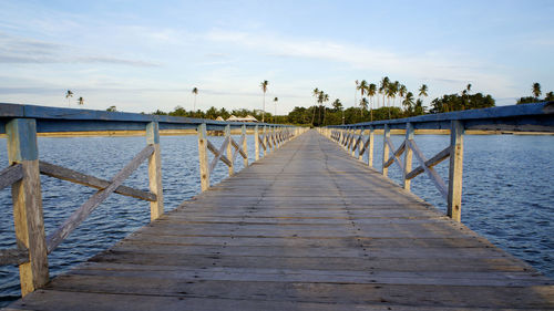 Empty wooden pier leading towards sea against sky