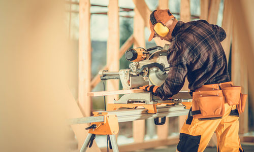 Construction worker cutting wood with equipment