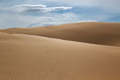 Sand dunes in desert against sky