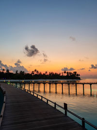 Pier over sea against sky during sunset