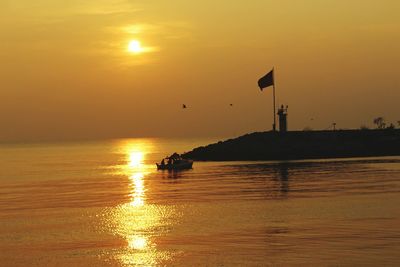 Silhouette boat in sea against sky during sunset