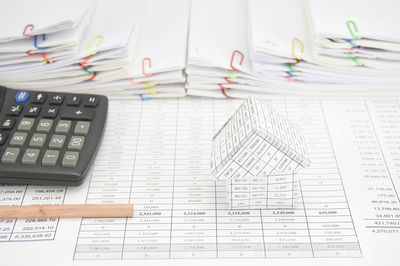 High angle view of model house and calculator on financial documents