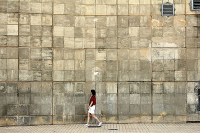 Rear view of woman walking on wall