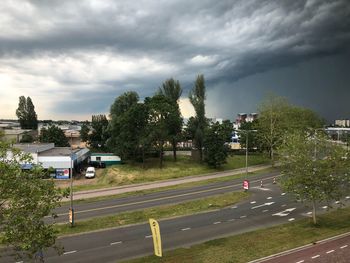 Road by trees against sky in city