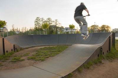 Full length of man skateboarding on road against clear sky