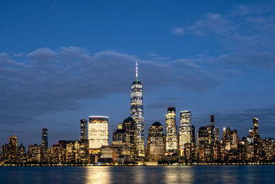 Illuminated buildings in city against cloudy sky