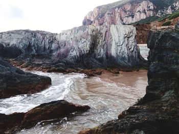 Rock formations by sea against sky