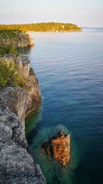 Rock formation by sea against sky