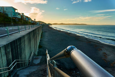 Scenic view of sea and beach with stairs against sky during sunrise