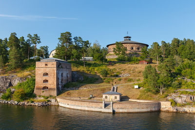 Buildings by river against sky