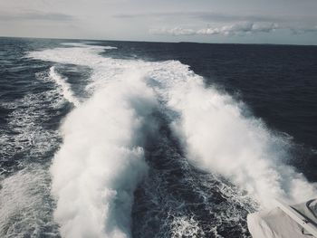 Waves splashing in sea against sky