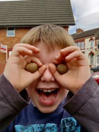 Portrait of boy holding stones over eyes