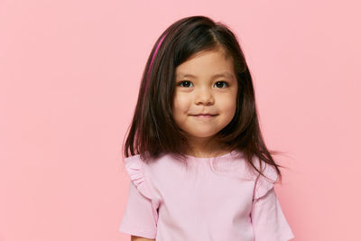 Portrait of young woman against pink background