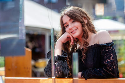 Portrait of smiling young woman sitting at sidewalk cafe