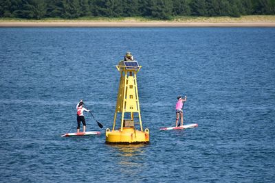 Rear view of women paddleboarding in lake