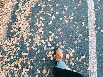 Low section of man standing on autumn leaves