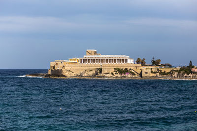 View of building by sea against sky