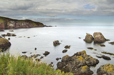 Rocks on sea shore against sky