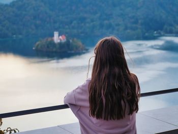 Rear view of woman standing against lake