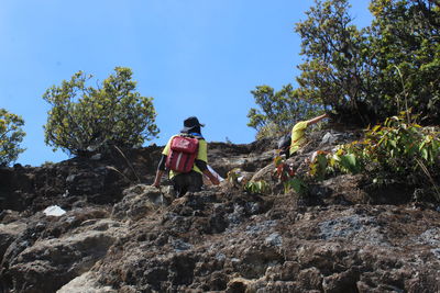 Rear view of man standing on rock against sky