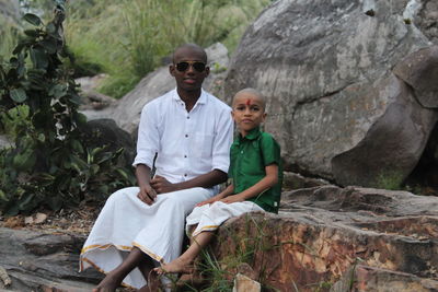 Portrait of sibling sitting on rock