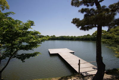 Wooden posts in lake against sky