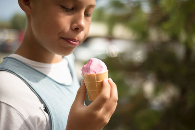 The boy holds a pink ice cream in his hand. pleasure. positive emotions.