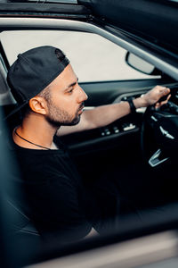 Side view of young man in car