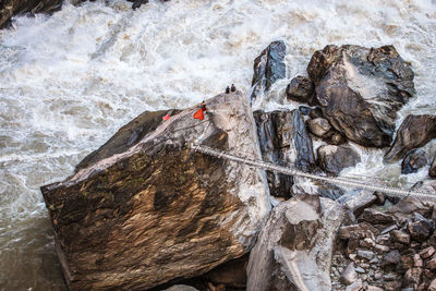 High angle view of bridge on rocks with sea waves splashing