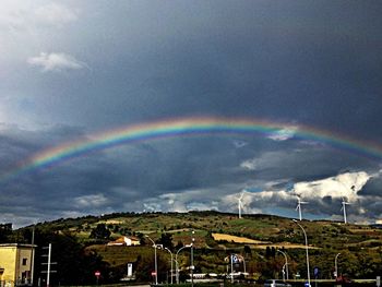 Rainbow over landscape against cloudy sky